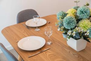 a wooden table with two plates and a vase of flowers at Apartamento Verde Atlântico in Ponta Delgada +33 photos