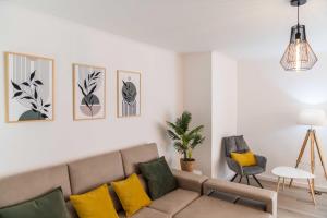 a living room with a couch and yellow pillows at Apartamento Verde Atlântico in Ponta Delgada