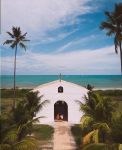 una chiesa sulla spiaggia con due persone in piedi sulla porta di Casa em São Miguel dos milagres rota dos milagres a São Miguel dos Milagres Altre 17 foto