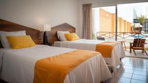 a hotel room with two beds and a balcony at Monaco Chicama Beach in Puerto Chicama