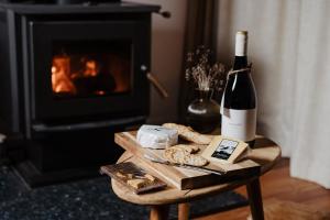 a bottle of wine and cheese on a table next to a fireplace at Kangaroo Ridge Retreat in Healesville