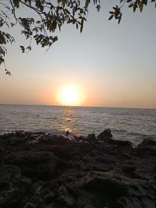 a sunset over a body of water with rocks at Paraíso de Deus in Colares