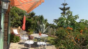 Un patio con una mesa y sillas y una sombrilla. en Villa Carpe Diem, en Le Lavandou