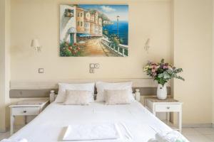 カラミツィにあるNontas Home 22の白いベッドと壁に絵画が飾られたベッドルーム1室