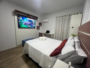 a bedroom with a bed with a tv on the wall at Aconchego no Canto do Forte - Ar Condicionados - Tvs Grandes - Wi-fi e Estacionamento Incluso! in Praia Grande +35 photos