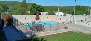 una piscina con due sedie e un ombrellone di Casa de campo a Santana do Livramento