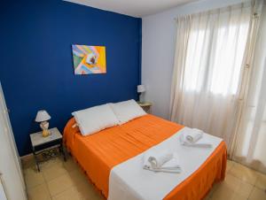 ein Schlafzimmer mit einem Bett mit orangefarbener Bettwäsche und einer blauen Wand in der Unterkunft Depto. Alvear 972 in San Salvador de Jujuy