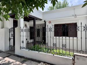 a white house with a black fence with a gate at La Casa de Ignacia in Estación Ramallo