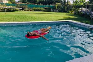 a child laying on a raft in a swimming pool at Posada Los Horneros in Coronel Suárez