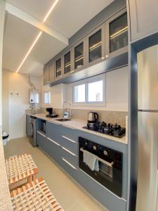 a kitchen with blue cabinets and a stainless steel refrigerator at Conforto e modernidade na praia 400m - mar in Porto Belo