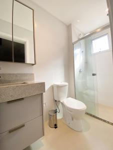 a white bathroom with a toilet and a shower at Conforto e modernidade na praia 400m - mar in Porto Belo