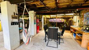 a room with a table and chairs and an umbrella at Mata Nui Eco Hostel in Hanga Roa
