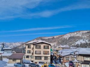 a town with cars parked in the snow and a building at Bamboo-Hill -OT- in Nozawa Onsen