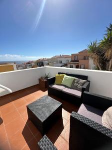 a balcony with couches and tables on a roof at Paradise Costa Bella in Fasnia
