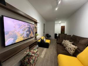 a living room with a large flat screen tv on a wall at Aconchego no Canto do Forte - Ar Condicionados - Tvs Grandes - Wi-fi e Estacionamento Incluso! in Praia Grande