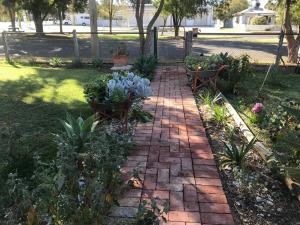 un chemin en briques dans un jardin avec des fleurs et des plantes dans l'établissement Country Style Cottage, à Ouyen