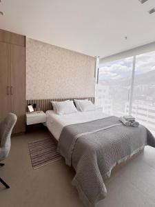 a bedroom with a large bed and a chair at New Mini Suite, La Carolina in Quito