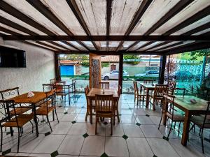 a restaurant with tables and chairs on a tiled floor at Pousada Abacateiro in Búzios