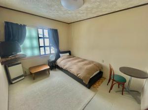 a bedroom with a bed and a table and a window at Bamboo-Hill -OT- in Nozawa Onsen