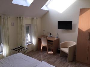 a room with a bed and a desk and a television at Pension im Wirtshaus Himberg in Bad Honnef am Rhein