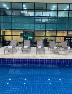 a group of chairs sitting next to a swimming pool at Suites in B Tree Av Paulista in Sao Paulo