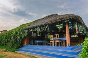 a house with a thatched roof with a table and chairs at Red Earth Kabini in Begūr