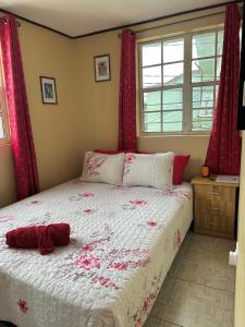 a bedroom with a large bed with red curtains at La Caille Créole in Roseau