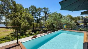 a swimming pool with an umbrella in a yard at Rivers Edge Oasis -Karuah, Infinity Pool and Private Cinema room in Karuah