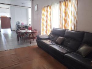 a living room with a black leather couch and a table at R&J homestay in Tina-an