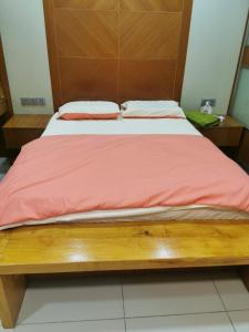 1 cama con cabecero de madera y manta roja en A&O HomeKB, en Kota Bharu