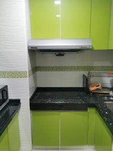 una cocina con armarios verdes y encimeras negras en A&O HomeKB, en Kota Bharu