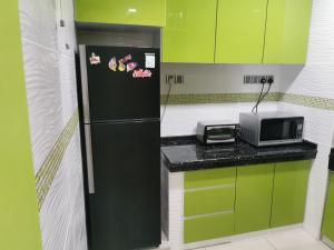 cocina con nevera negra y microondas en A&O HomeKB, en Kota Bharu