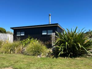 a black house with plants in front of it at Tau Studio - Boutique Accommodation in Ohakune +7 photos
