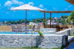 a patio with a table with an umbrella and chairs at Villa Mar - Baia Formosa in Baía Formosa