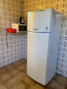 a white refrigerator in a kitchen with a microwave at Hostel 858 in Pelotas