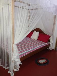 a bed with a canopy with white curtains at Rustic Inn in Mirissa