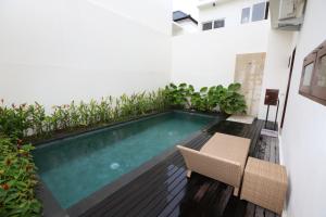 a swimming pool in the middle of a building with two chairs at Rivera Villa Seminyak in Seminyak