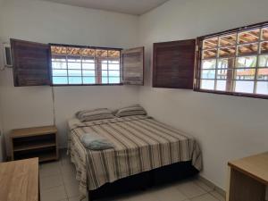 a small bedroom with a bed and two windows at Lucena praia in Lucena