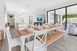 ein Esszimmer mit einem langen Tisch und weißen Stühlen in der Unterkunft Pengana Beach Retreat Mornington Peninsula in Rosebud