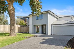ein weißes Haus mit einem Baum und einer Auffahrt in der Unterkunft Pengana Beach Retreat Mornington Peninsula in Rosebud