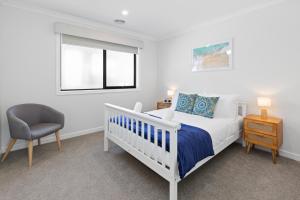 ein Schlafzimmer mit einem Bett und einem Stuhl und einem Fenster in der Unterkunft Pengana Beach Retreat Mornington Peninsula in Rosebud