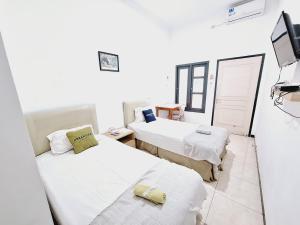 a room with two beds and a television in it at Urbanview Roemah Tanjung Blitar in Blitar