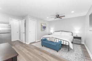a white bedroom with a bed and a blue chair at Downtown Kimmswick Studio-Renovated-Prime Location in Imperial