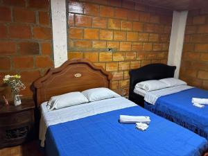 two beds in a room with a brick wall at Finca Hotel La Paloma in Quimbaya