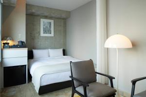 a bedroom with a bed and a chair and a lamp at TONES Osaka in Osaka +39 photos