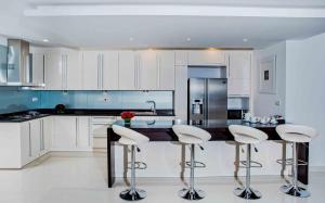 a kitchen with white cabinets and a island with bar stools at Platinum One Suites in Colombo