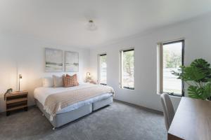 a white bedroom with a bed and two windows at Stylish Family Retreat by Hawley Beach in Hawley Beach