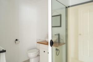 a bathroom with a toilet and a glass shower door at Stylish Family Retreat by Hawley Beach in Hawley Beach +14 photos