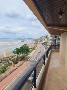 d'un balcon avec vue sur la plage et les bâtiments. dans l'établissement Apartamento Pé na Areia, a 12 min do Beto Carrero, à Navegantes