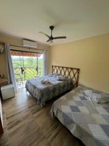 a bedroom with two beds and a ceiling fan at Pousada Camping dos Ypês in Guapimirim